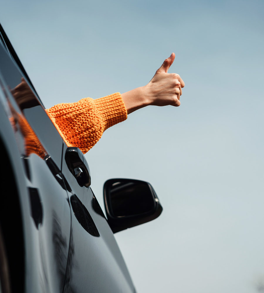Hand, die aus einem Auto herausgestreckt wird und dank eines erfolgreichen MPU-Vorab-Checks einen Daumen nach oben zeigt.