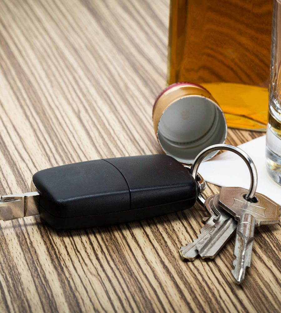 Autoschlüssel, der neben einem Glas und einer Flasche mit Alkohol liegt